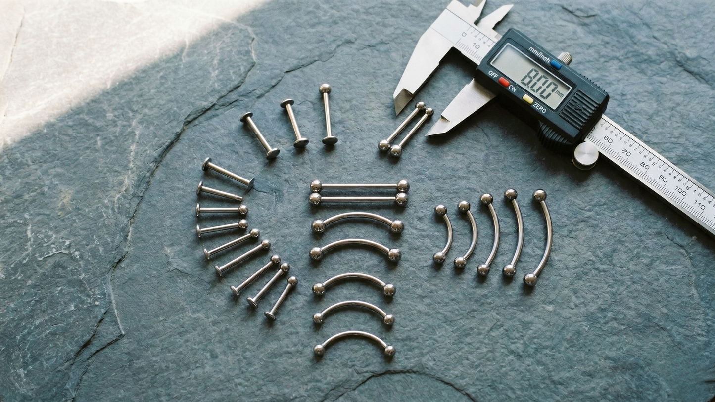 a digital caliper, and several titanium piercing pieces 