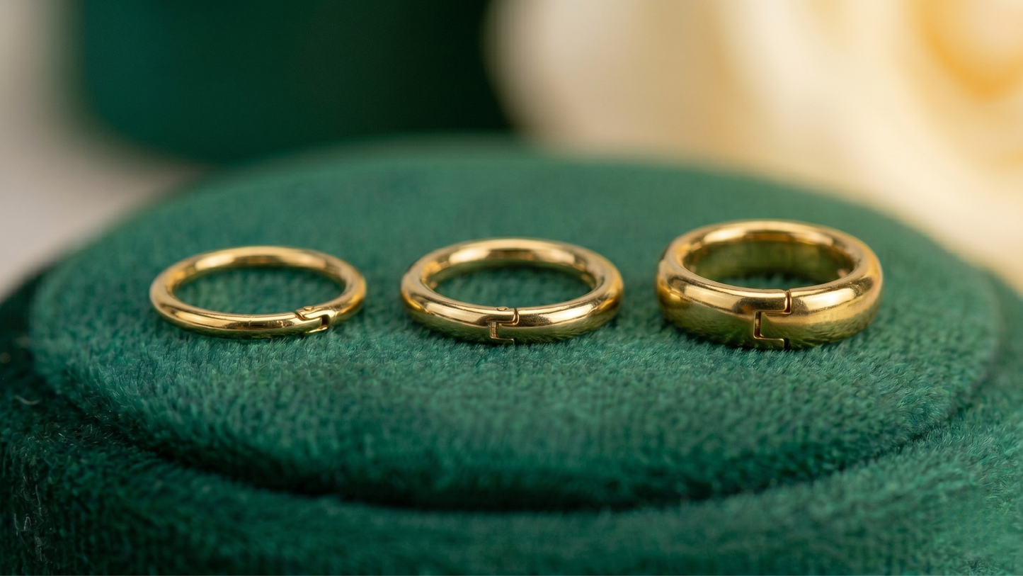 three small gold-toned piercing hoopd side by side on a velvet pad