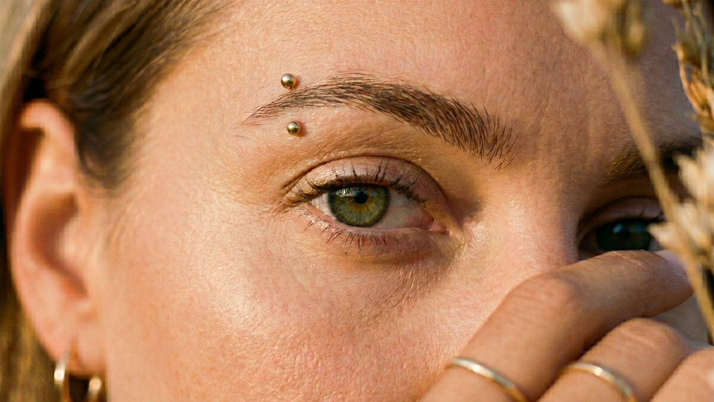  a small gold PVD titanium curved barbell through the outer brow