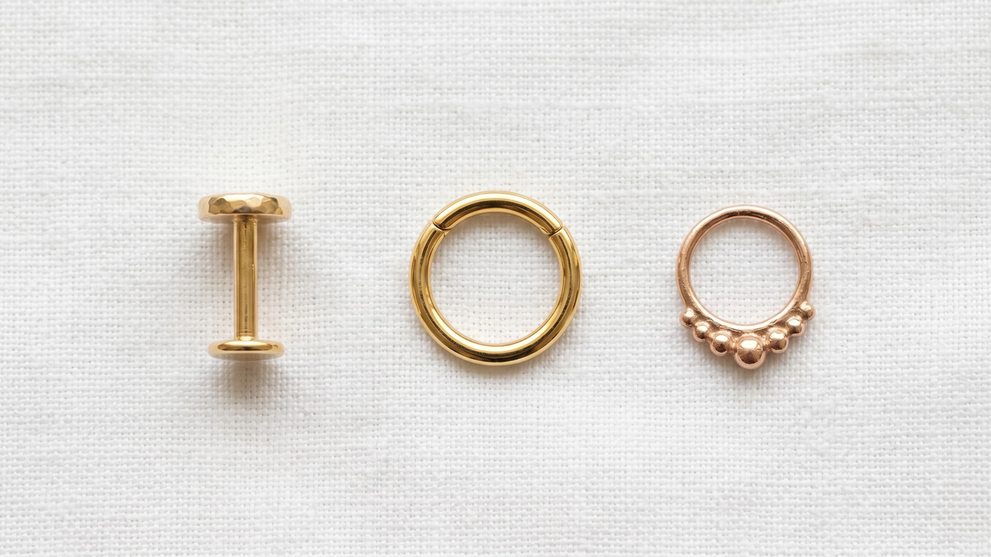 lay of three different gold-toned piercing pieces side by side