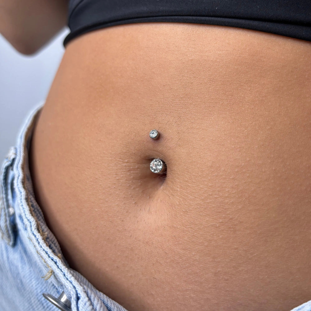 Mulher a usar piercing no umbigo com zircónias em titânio da loja online de piercings online, Piercepective. Piercings de qualidade e joalharia corporal segura.