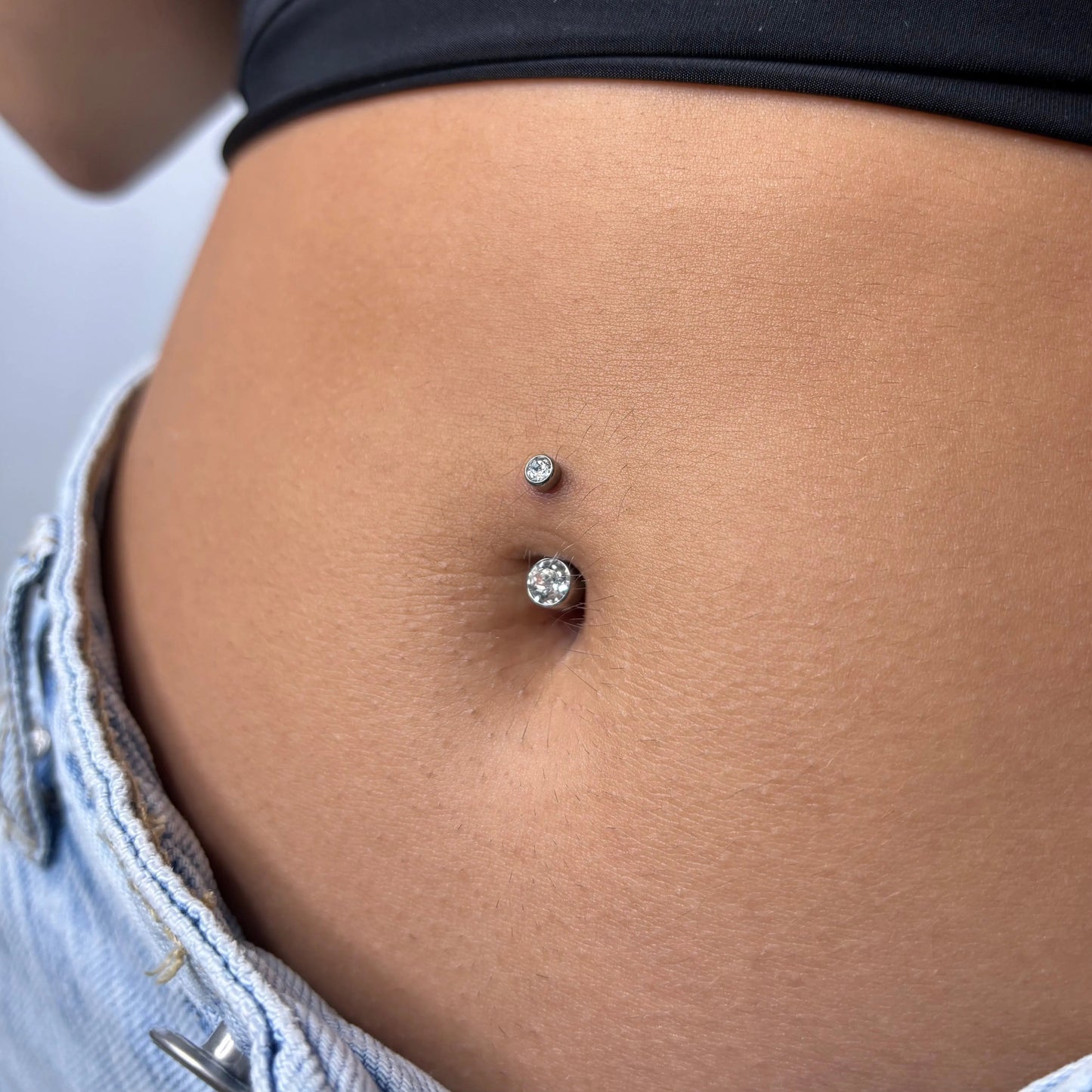 Mulher a usar piercing no umbigo com zircónias em titânio da loja online de piercings online, Piercepective. Piercings de qualidade e joalharia corporal segura.