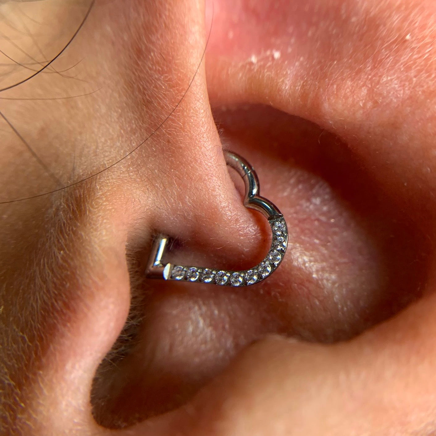 
                  
                    Argola coração cravejada com zircónias aplicada no tragus – titânio ASTM hipoalergénico
                  
                