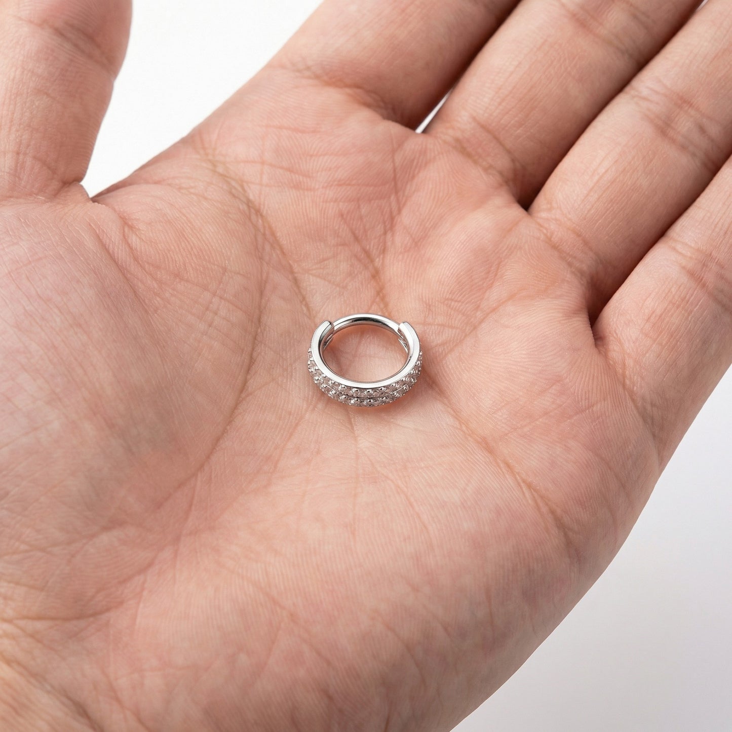 
                  
                    Argola dupla cravejada com zircónias e fecho clicker em titânio ASTM 
                  
                