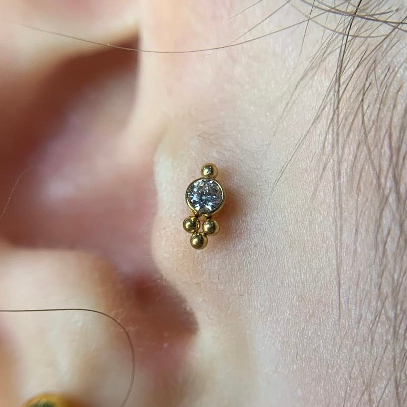 Labret com zircónia e missangas aplicado no tragus, em titânio PVD Gold com rosca interna